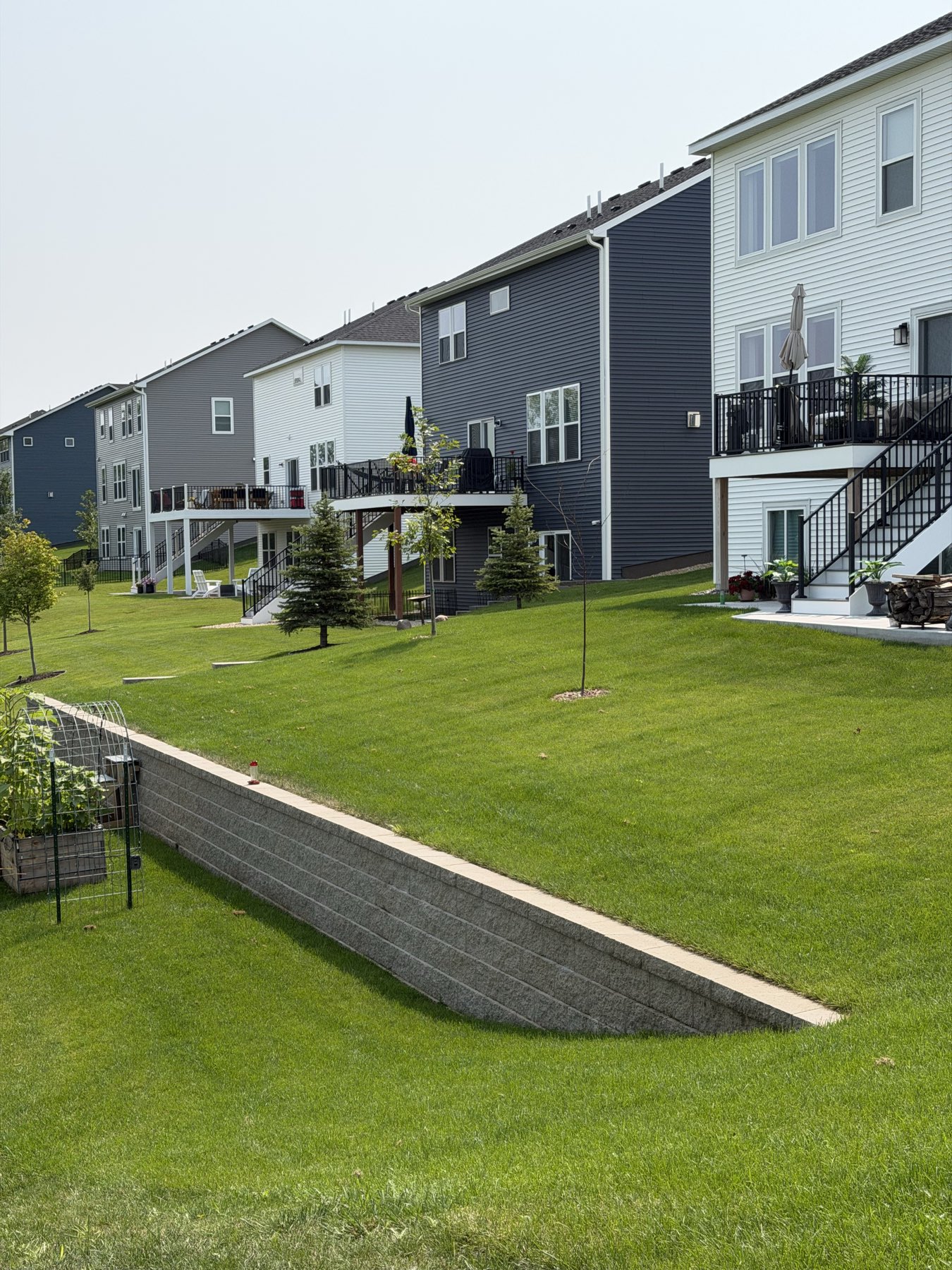 Segmental block retaining wall with cut cap holding a raised lawn behind the Norman residence